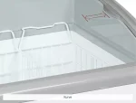 screenshot-34-6a2be9c049c2d - Gastro Inventar Inside view of a curved glass-top freezer with a white wire basket inside, and a red measurement arrow on the lid.