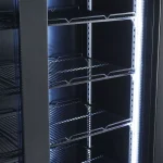 Empty black metal server rack with multiple adjustable wire shelves and bright vertical LED lighting along the right edge in a data-center setting.