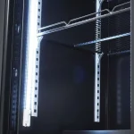 Open server rack with metal mounting rails, a bright vertical LED strip on the left, and empty shelves ready for equipment.