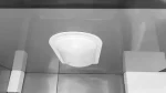 Round ceiling smoke detector with vents mounted on a tiled ceiling, white and central in the frame.