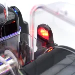 Close-up of a glossy black motorcycle with red LED tail light and blue accent lights on the body.